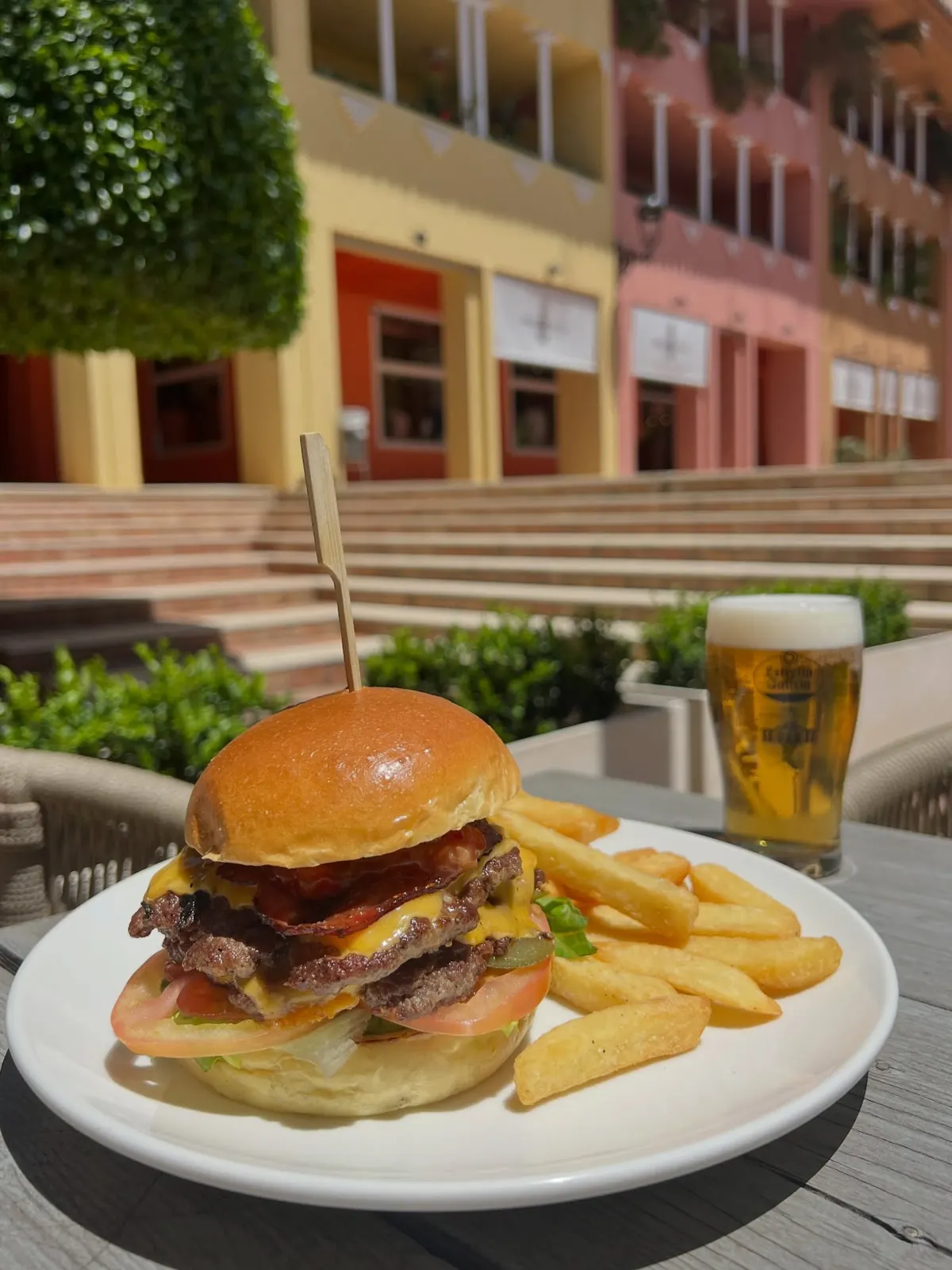 A burger and chips with a cold beer and the port behind