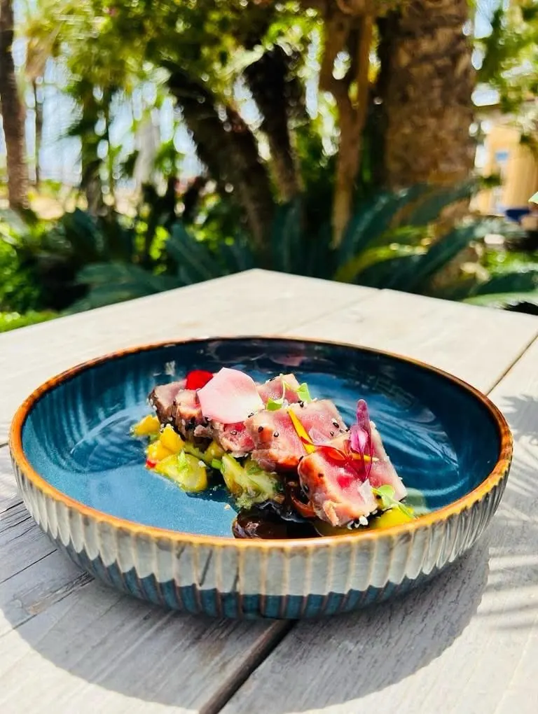 Gambas and ceviche in a blue bowl with the garden behind