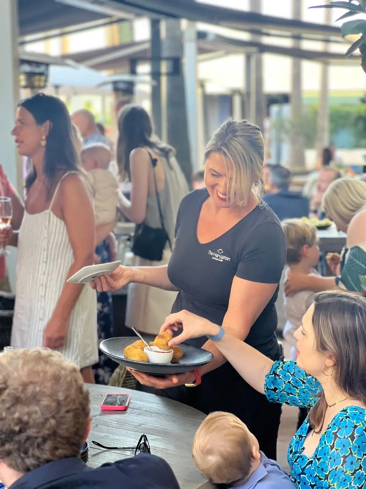 A member of staff serving canapés to guests at a busy event