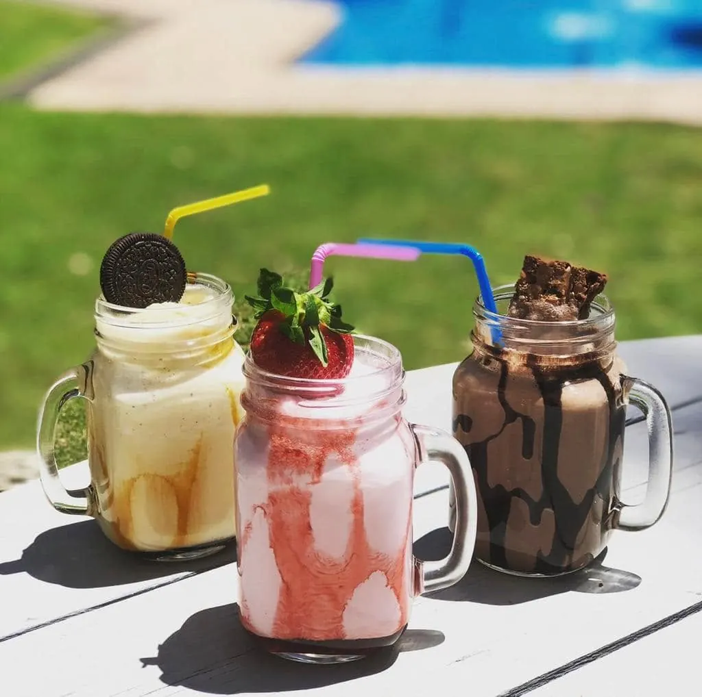Three tall milkshakes topped with cream and chocolate