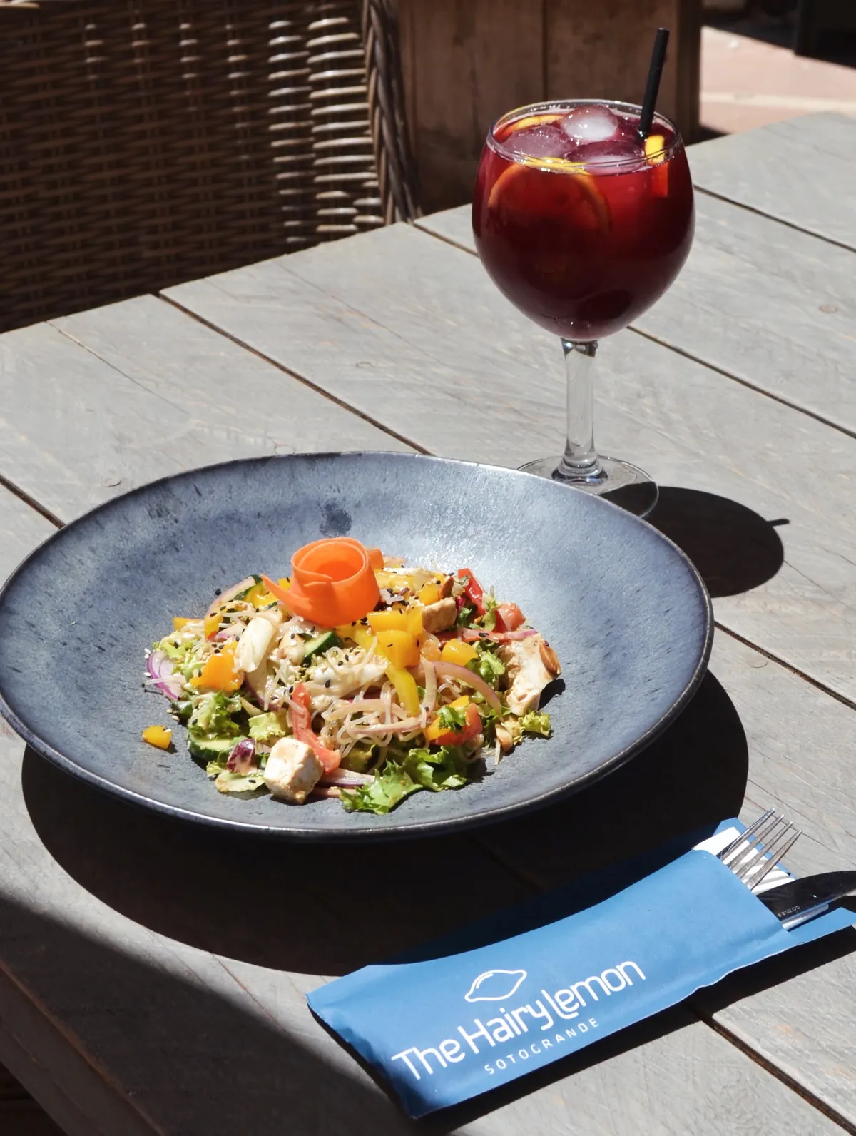 A glass of sangria beside a salad on the terrace